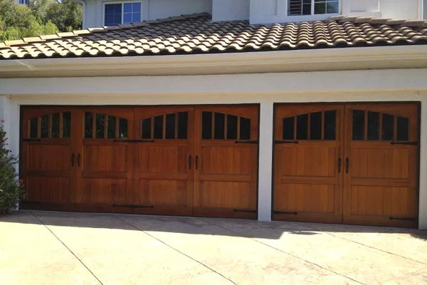 An exterior view of a home featuring side-by-side wooden carriage-style garage doors, highlighting the visual comparison of a single garage door vs. double garage door layout.