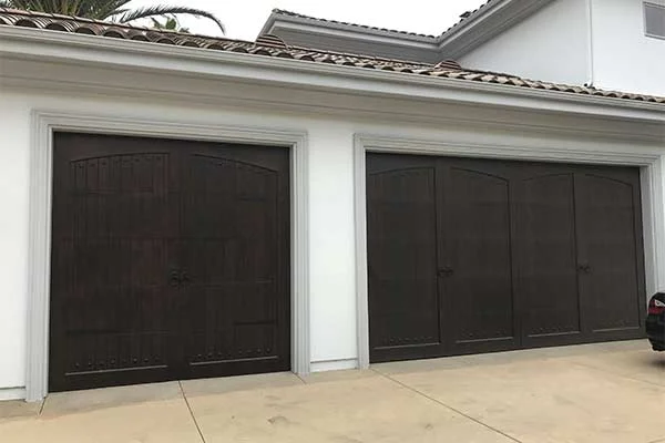 An exterior view of a home featuring dark-stained single and double carriage-style wooden doors, ideal for tips on how to choose the best modern wood garage door.