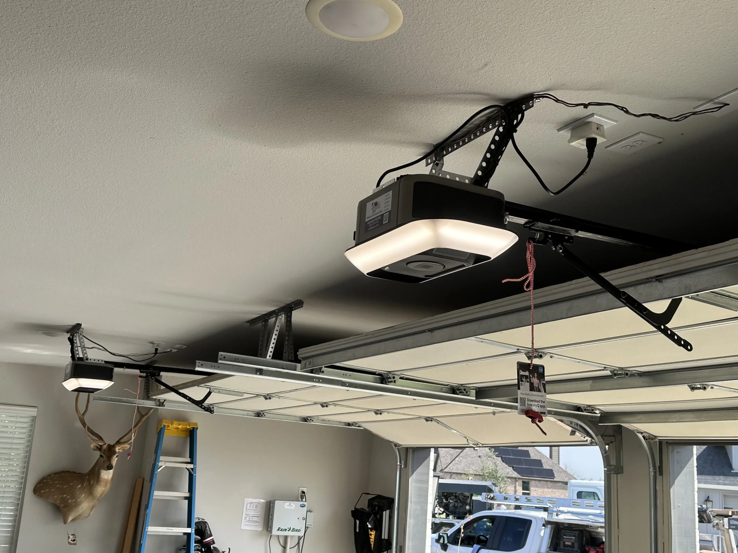 An interior view of a residential garage with two ceiling-mounted automatic motor units, perfect for articles exploring garage door opener compatibility.