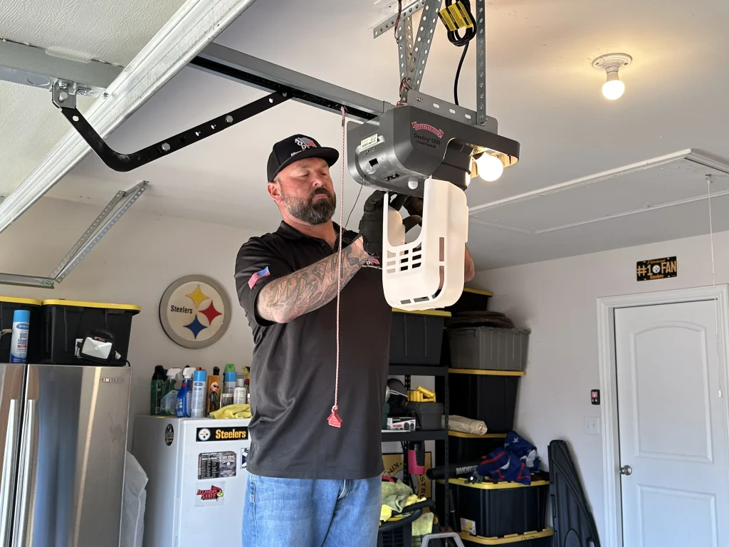 A service technician adjusting an overhead motor unit inside a home garage, ideal for residential clients looking for professional garage door openers near me.