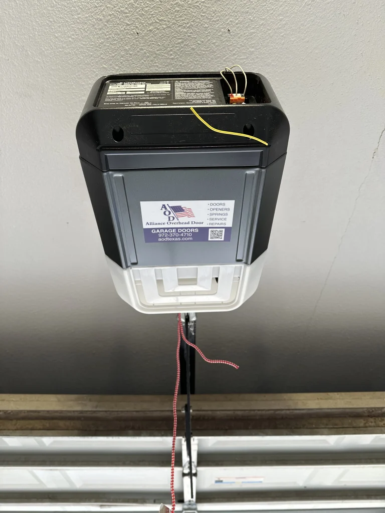 A view from below of a ceiling-mounted LiftMaster opener unit with an Alliance Overhead Door service sticker, illustrating the vital role of garage door openers in home security and safety.