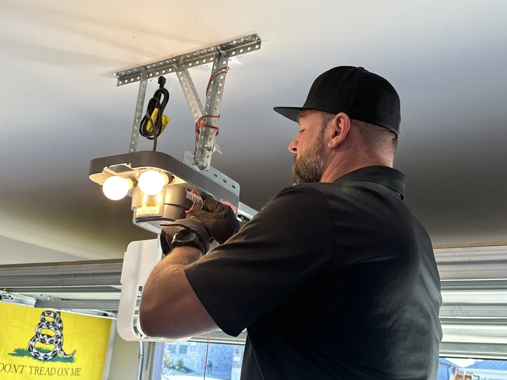 A service technician working on the internal wiring and components of an overhead motor unit, providing a clear visual example of what is a garage door opener system.