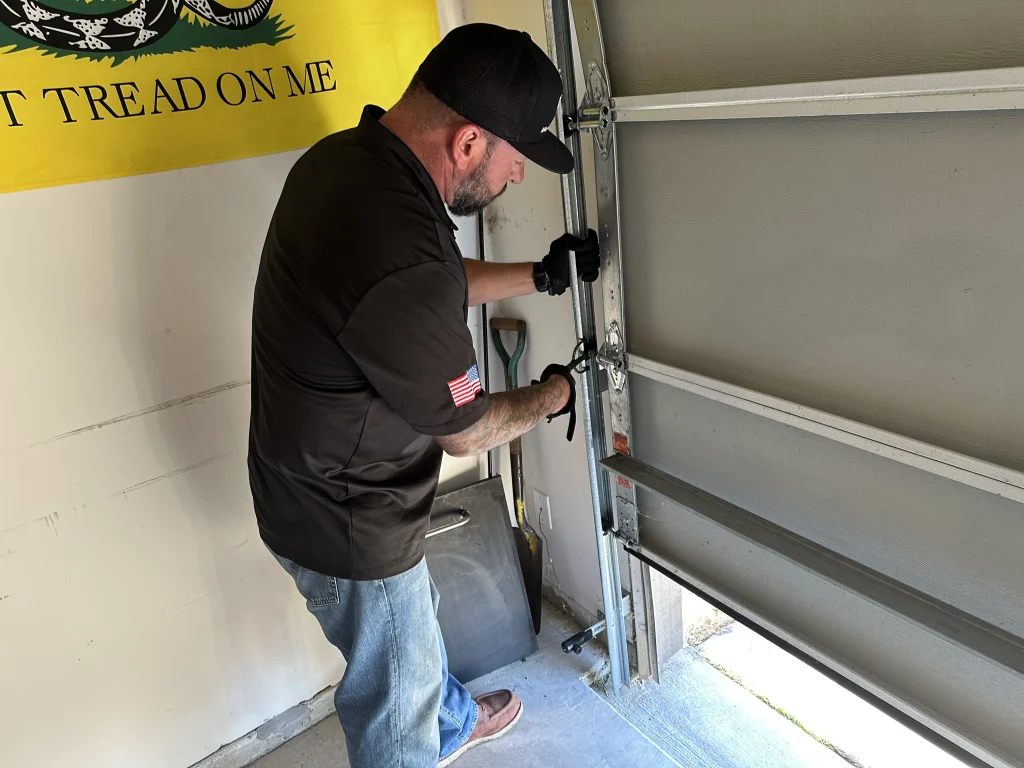 A technician inspecting the hinges and tracking that connect sectional sheets together, providing a practical look at how do garage door panels work.