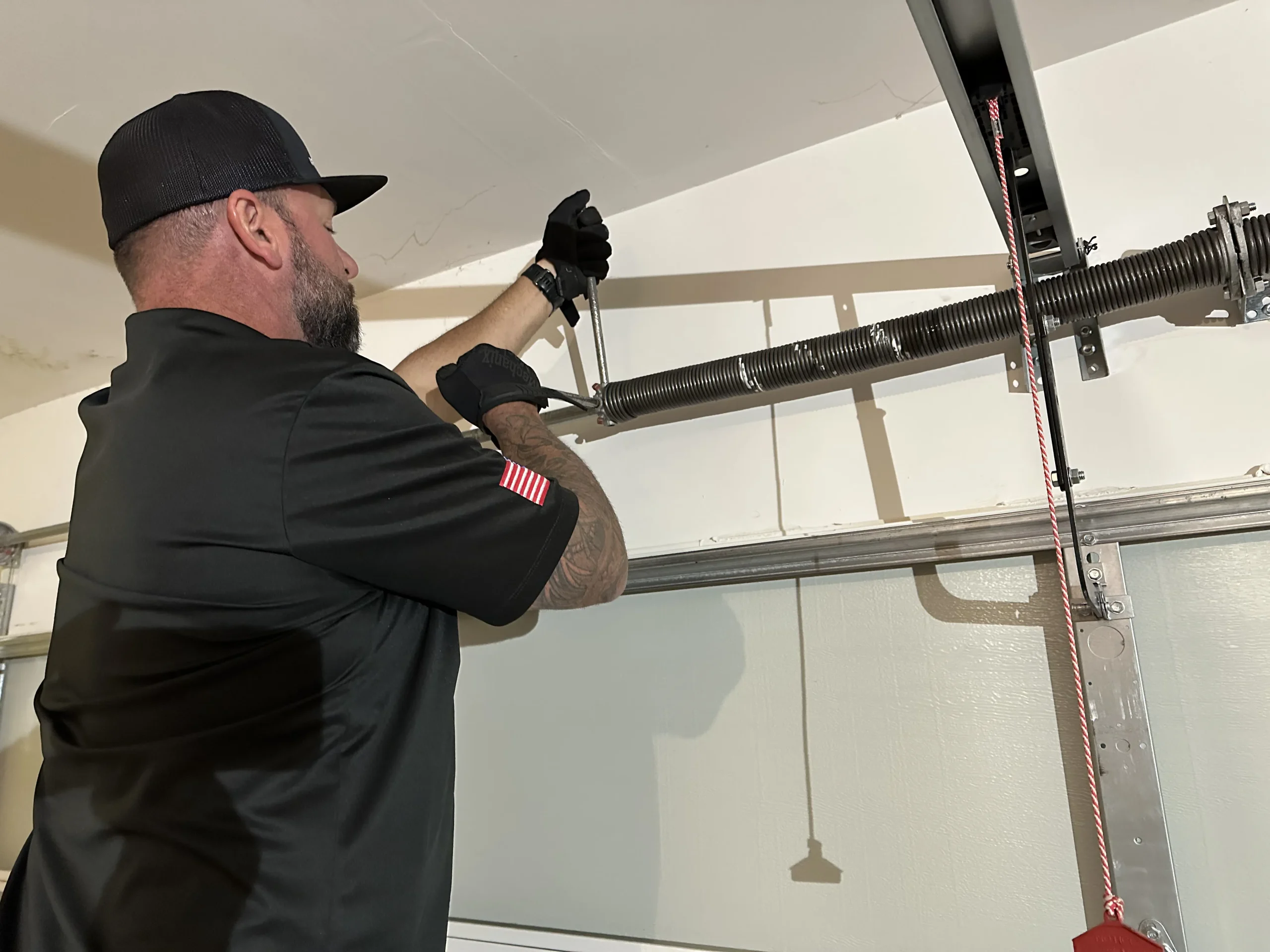 A close-up view of a garage door technician using winding bars to service a overhead system during a Broken Torsion Spring Repair.