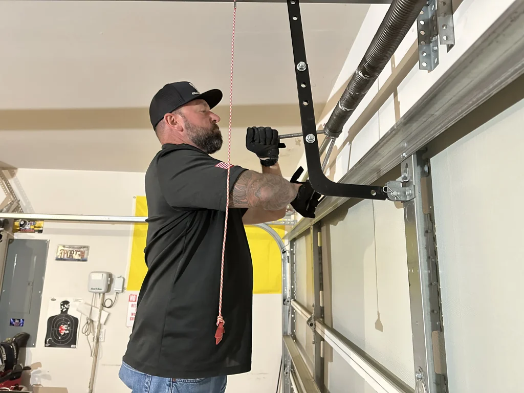 A professional technician using winding bars to precisely balance a torsion spring system, representing Trusted Garage Door Spring Experts.